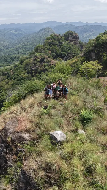 Hikers on top of the Peñón K59 with green mountains all around